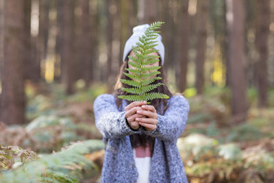 Full length of man holding plant in forest