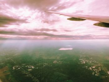 Close-up of airplane wing over landscape against sky