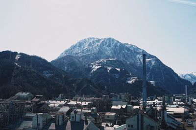 Aerial view of townscape by mountains against clear sky