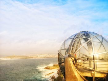 Ferris wheel by sea against sky