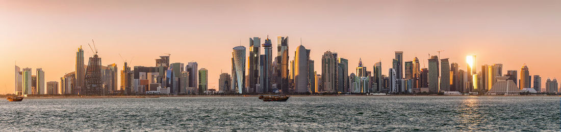 Panoramic view of buildings at waterfront against sky during sunset