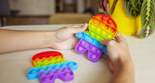 Close-up of hand holding multi colored toy on table