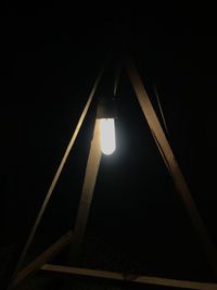 Low angle view of illuminated lamp against black background