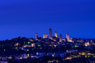 Illuminated buildings against clear blue sky at night