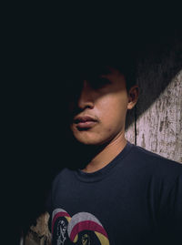 Portrait of young man looking away against wall