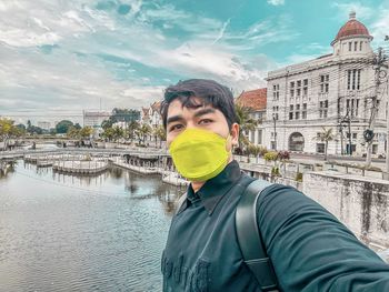 Side view of man standing by canal against sky