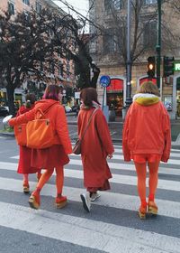 Rear view of people walking on cross in city