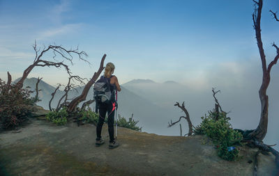 Rear view of woman standing on mountain against sky