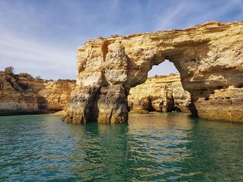 Rock formation by sea against sky