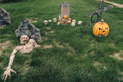 Many colorful halloween decorations, skeletons, scarecrows at driveway and front lawn of house.