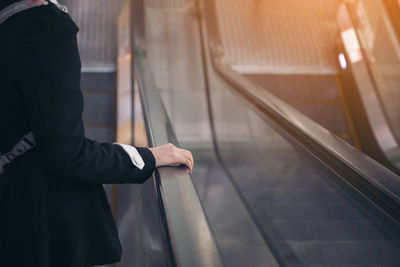 Midsection of man standing on escalator