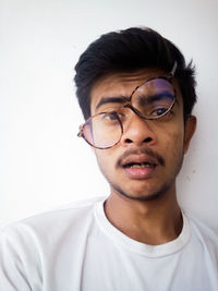 Portrait of young man wearing eyeglasses against white background