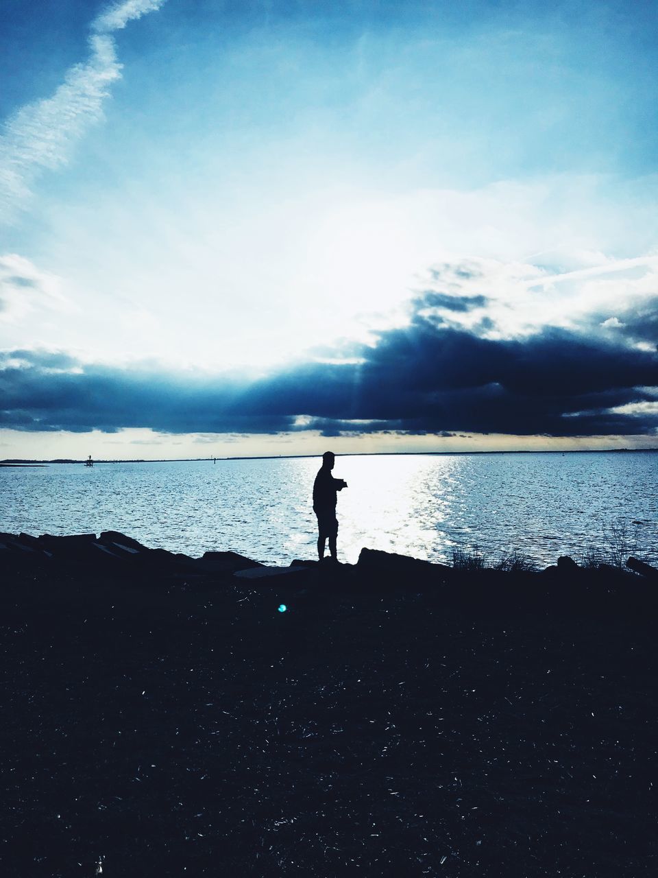 SILHOUETTE MAN STANDING ON SHORE AGAINST SKY