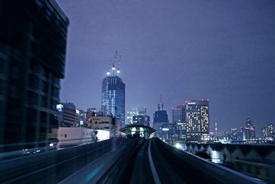 Illuminated buildings in city against sky at night