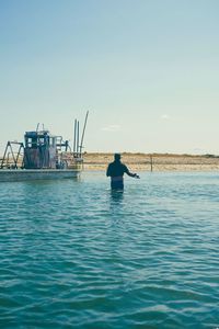 Silhouette man in sea against clear sky