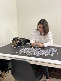 Woman with dog sitting on table against wall