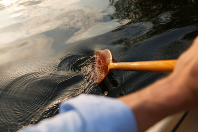 Close-up of hand holding paddle in water