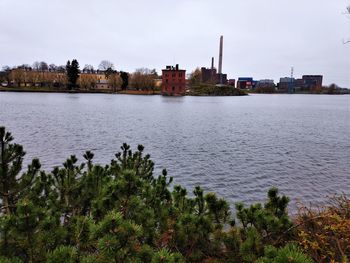 Scenic view of river by buildings against sky