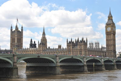 Arch bridge over river and buildings against sky in city