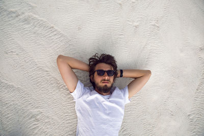 Man with a beard in a white t-shirt and shorts rest on a white mountain in pamukkale