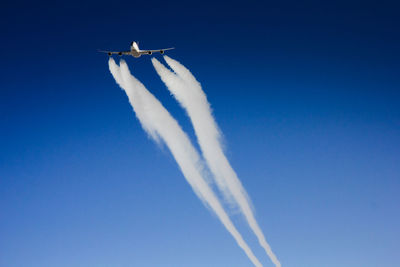 Low angle view of airplane flying in clear blue sky