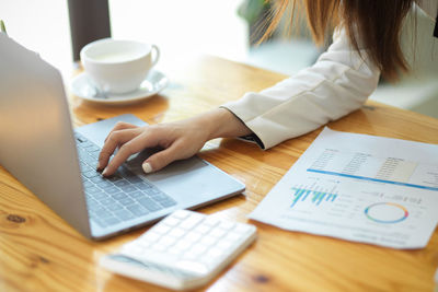 Midsection of woman using laptop on table