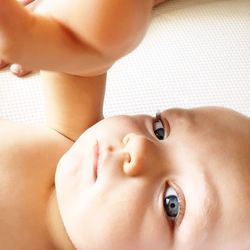 High angle portrait of cute shirtless baby boy lying on bed at home