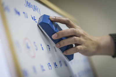 Cropped hand of female student erasing text on whiteboard