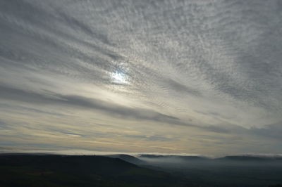 Scenic view of landscape against cloudy sky during sunset