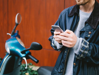 Close-up of man using mobile phone by scooter