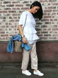 Young woman standing against brick wall