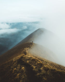 Scenic view of foggy mountains against sky with person