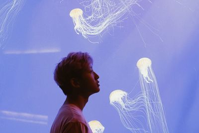 Side view of young man standing in aquarium