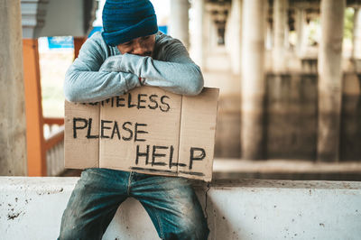 Midsection of man sitting on street in city