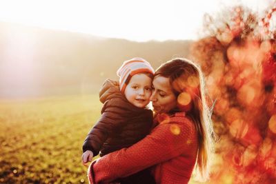 Portrait of happy mother and daughter on field against sky