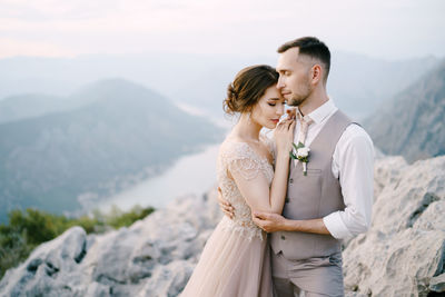 Side view of young woman standing against mountain