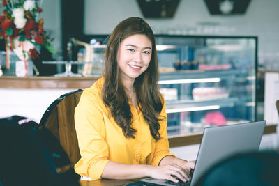 Portrait of a smiling young woman using phone