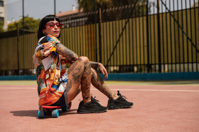 Caucasian girl with tattoos and short black hair on a sports court