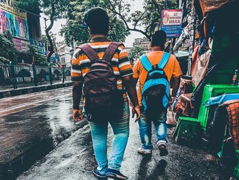 Rear view of people walking on road in city