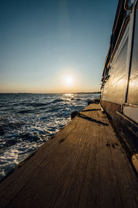 Wooden boat on sea against sky during sunset