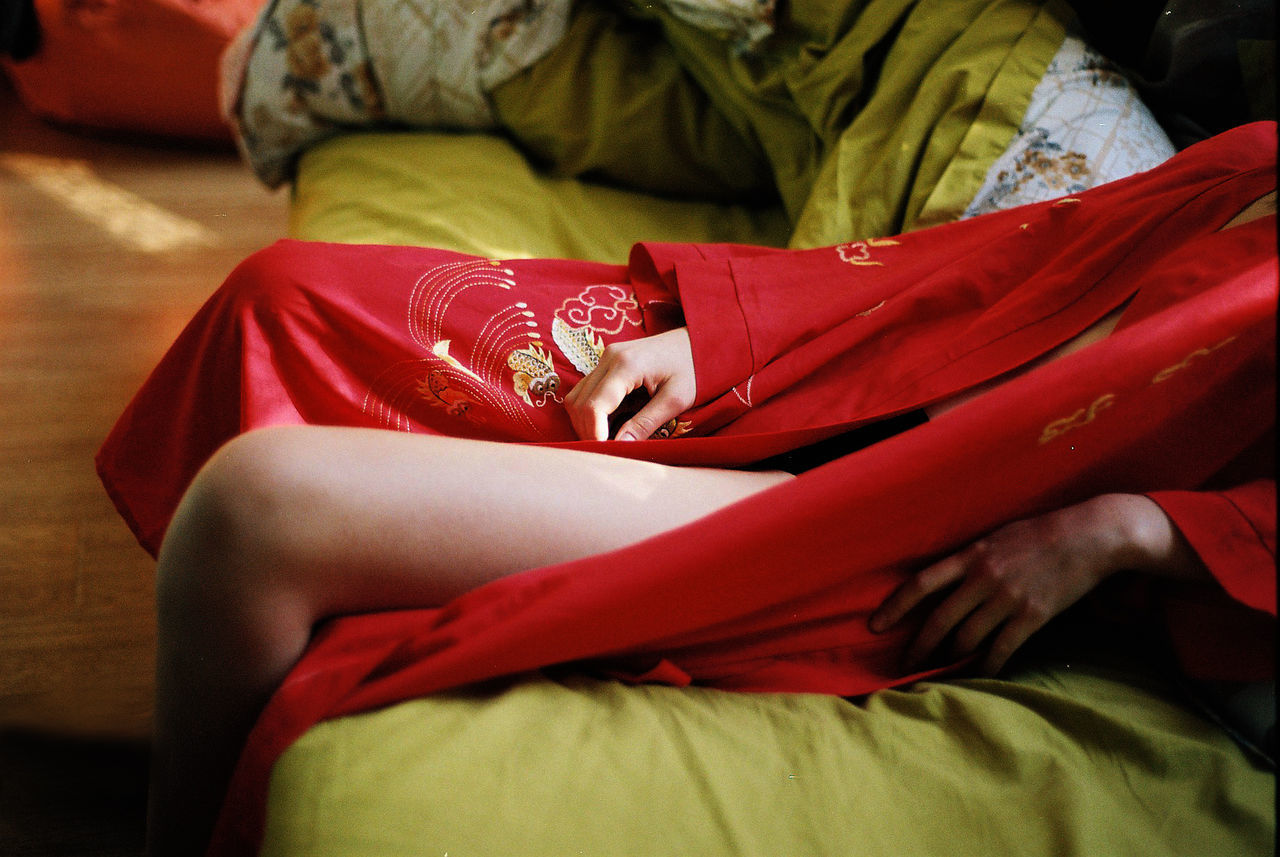 MIDSECTION OF WOMAN WITH RED SITTING AT HOME