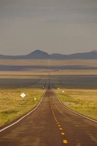 Road by landscape against sky during sunset