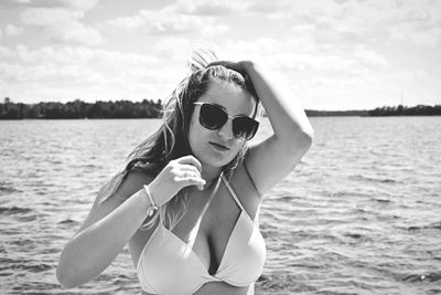 Beautiful woman wearing sunglasses and bikini against sea