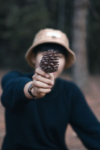 Close-up of man covering face with pine cone