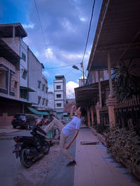 Man riding motorcycle on street amidst buildings in city