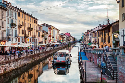 Buildings amidst canal at naviglio grande against sky