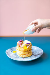 Close-up of hand pouring honey on dessert