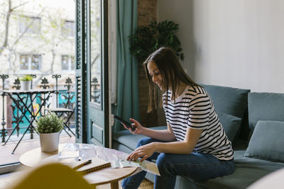 Midsection of woman using mobile phone while sitting on table