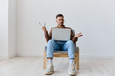 Portrait of woman using laptop while sitting on sofa at home