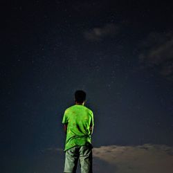 Rear view of man standing against star field at night